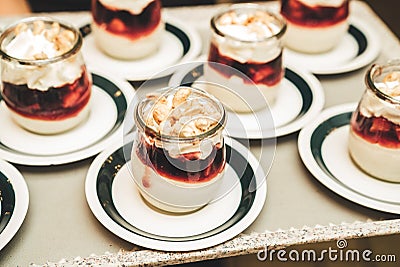 Rows of glasses with white-red sweet dessert decorated on top with cashew nuts. Self-serving buffet table. Celebration Stock Photo
