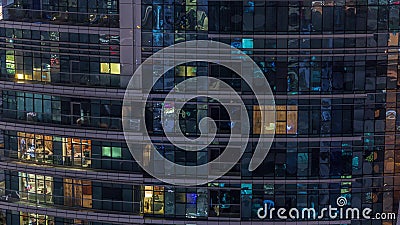 Rows of glowing windows with people in apartment building at night. Editorial Stock Photo