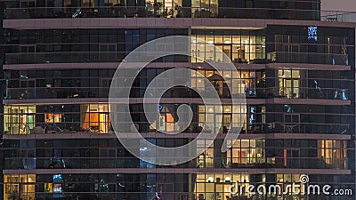 Rows of glowing windows with people in apartment building at night. Editorial Stock Photo