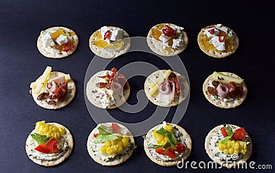 Rows of hors d`oeuvres crackers topped with variety of meats cheese spreads Stock Photo