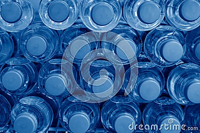 Rows of many transparent plastic bottles with drinking water supply in white refrigerator. Mineral water stack storage in fridge Stock Photo