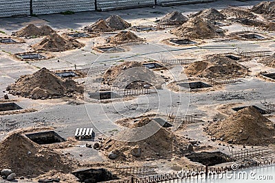 Rows of pits at a construction site. preparation of the site for the installation of piles. a pile of sand Stock Photo