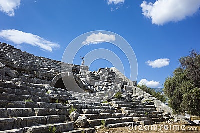 Rows of stone seats of ruins of Theatre in Letoon Ancient City in village Kumluova, Turkey. Sunny day, Tourist stands at top Stock Photo