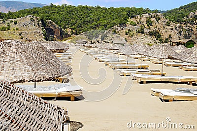 Rows of straw umbrellas on empty seaside beach Stock Photo