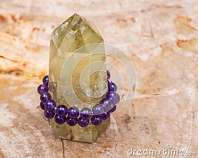 Royal purple Amethyst bead bracelet wrapped around Polished CITRINE single point on Natural Polished Petrified wood slab Stock Photo