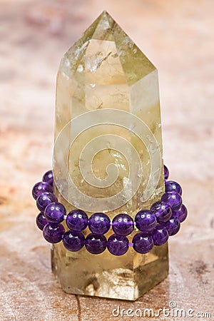 Royal purple Amethyst bead bracelet wrapped around Polished CITRINE single point on Natural Polished Petrified wood slab Stock Photo