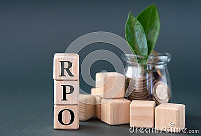 RPO - acronym on wooden cubes on the background of a glass jar with coins and green leaves Stock Photo