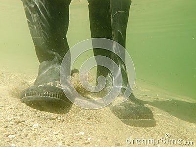 Rubber boots or gumboots underwater on sand ground Stock Photo