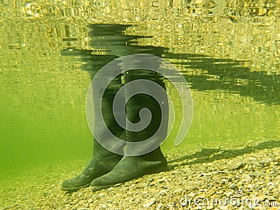 Rubber boots or gumboots underwater on sand ground Stock Photo