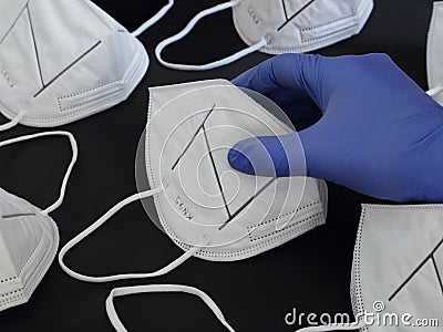 Rubber Gloved Hand Picking Up a KN95 Mask from a Collection Stock Photo