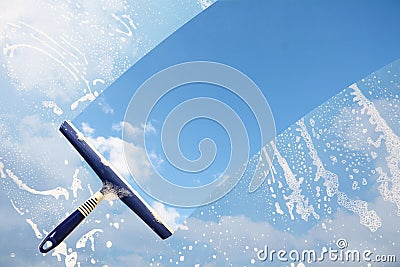 Rubber squeegee cleans a soaped window and clears a stripe of bl Stock Photo