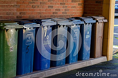 Rubbish bins with Stafford Borough Council logo on it. The green general waste, blue for recycling, and brown for compost and gard Editorial Stock Photo