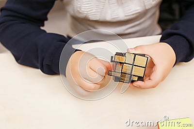 Rubik`s cube in children`s hands, closeup, white wooden background. Boy holding Rubik`s cube and playing with it Editorial Stock Photo