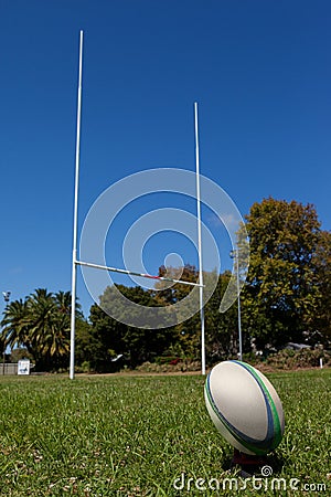 Rugby ball and post on grassy field against sky Stock Photo