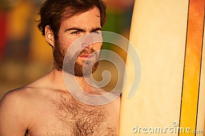 Rugged bearded male surfer portrait next to surf board Stock Photo