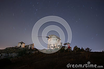 Ruin windmill in the night sky. A view of the stars of the Milky Way with a mountain top in the foreground. Stock Photo