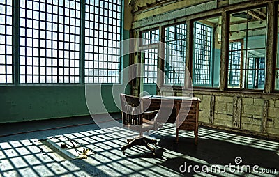 A ruined desk and a chair in an abandoned prison facility. Stock Photo