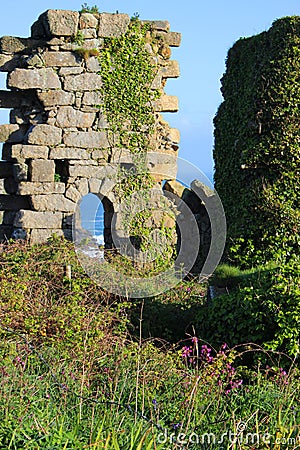 Ruined wall with archway on clifftop at derelict copper mine at Treen Cove on north coast of Cornwall, England Stock Photo