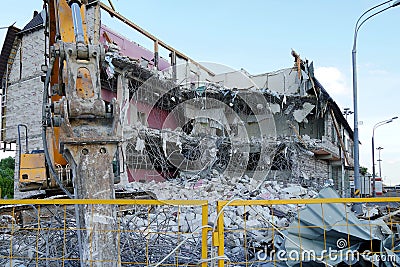 Ruined multi-storey building. An excavator demolishes a multi-storey building with a chisel tool. Technique destroys the building Stock Photo