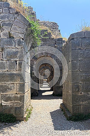 Ruins ancient city stone temple in ?zmir, top arches, keystones, columns, torso statue, high stone wall Stock Photo