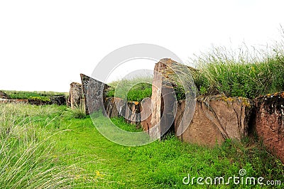 The ruins of an ancient sanctuary with the remains of walls and menhirs lying in the steppe tied with ritual ribbons Stock Photo