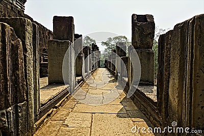 The ruins of the ancient temple of Angkor. The stone gallery on the castle terrace goes straight ahead. Stock Photo