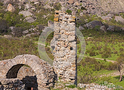 Ruins of the castle, elements of the buildings arch column stone on the background of the high mountains below grows the green Stock Photo