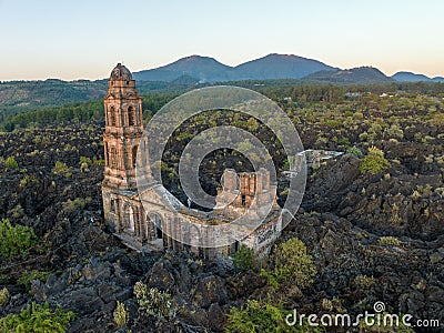 Ruins at Paricutin Volcano situated on a rocky landscape surrounded by lush greenery Stock Photo