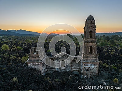 Ruins at Paricutin Volcano situated on a rocky landscape surrounded by lush greenery Stock Photo