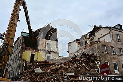 The ruins of an earthquake-damaged residential building with broken walls, brick fragments and roof are being dismantled by an Stock Photo