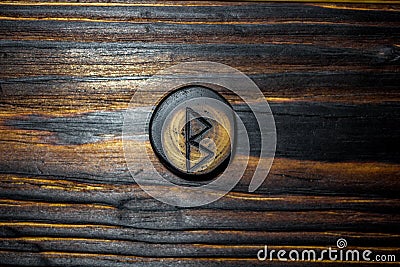 Rune Berkanan Bjarkan carved from wood on a wooden background Stock Photo