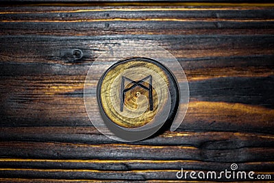 Rune Mannaz Mann carved from wood on a wooden background Stock Photo