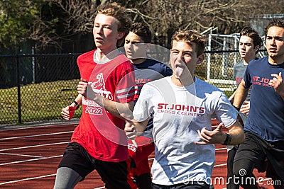 Runner gives hang loose sign with hands and sticks out his tongue while running in a group on a track Editorial Stock Photo