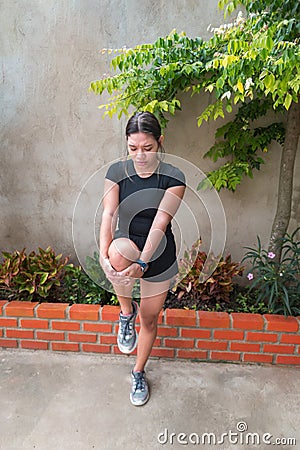 Runner holding sore leg, knee pain from running or exercising, jogging injury or cramp Stock Photo