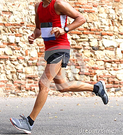 Runner runs fast race in town on a paved road Stock Photo