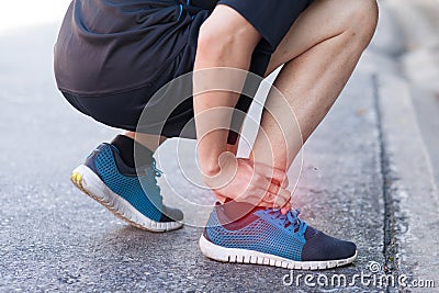 Runner touching painful twisted or broken ankle. Athlete runner training accident. Sport running ankle sprain. Stock Photo