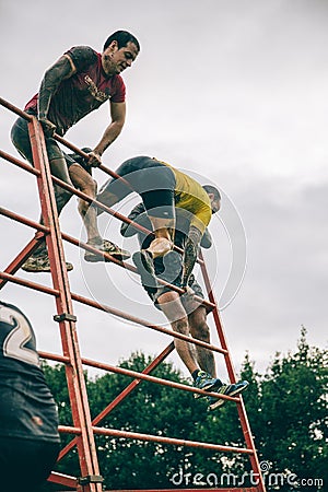 Runners climbing structure in a test of extreme obstacle race Editorial Stock Photo