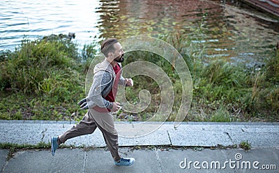 Running beardy male on river bank in the city. Stock Photo