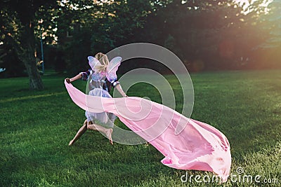 running blonde white Caucasian child kid girl with long hair wearing pink fairy wings and tutu tulle skirt Stock Photo