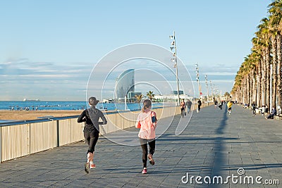 Running jogging on Barcelona Beach, Barceloneta. Healthy lifestyle people runners training outside on boardwalk. Multiracial coup Editorial Stock Photo