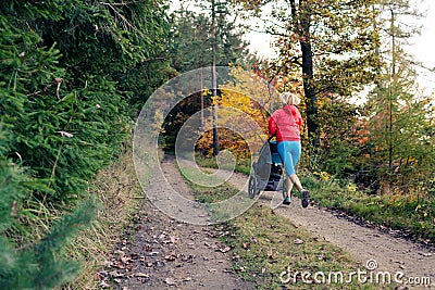 Running mother with stroller enjoying motherhood at autumn sunset Stock Photo