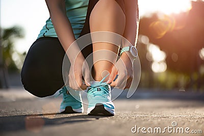 Running shoes - closeup of woman tying shoe laces. Female sport fitness runner getting ready for jogging in garden background Stock Photo