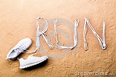 Running shoes and run sign made of shoelaces, sand Stock Photo