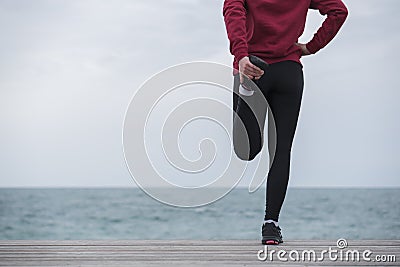 Running stretching before running. Athlete on the seacoast. Stock Photo