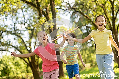 Running two joyful girls with toy and boy Stock Photo