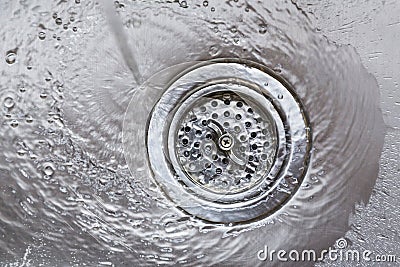 Running water flowing going down drain in stainless steel kitchen sink Stock Photo