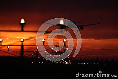 Silhouette of plane landing, runway lights, orange effect Stock Photo