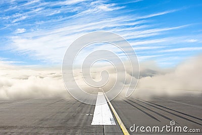 Runway road wrapped in dense low fog, clear blue sky from above. The concept of bad weather at the airport, the delay in the Stock Photo