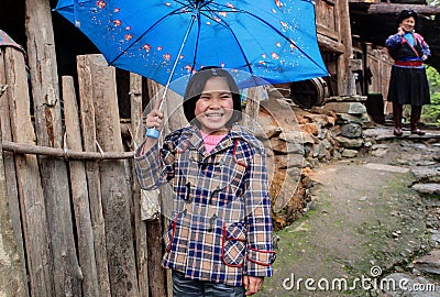Rural Asian girl, about 8 years , hiding blue umbrella and laugh Editorial Stock Photo