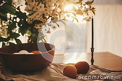 Rural Easter still life. Natural eggs and vintage candle on linen fabric on background of rustic table with cherry flowers and Stock Photo